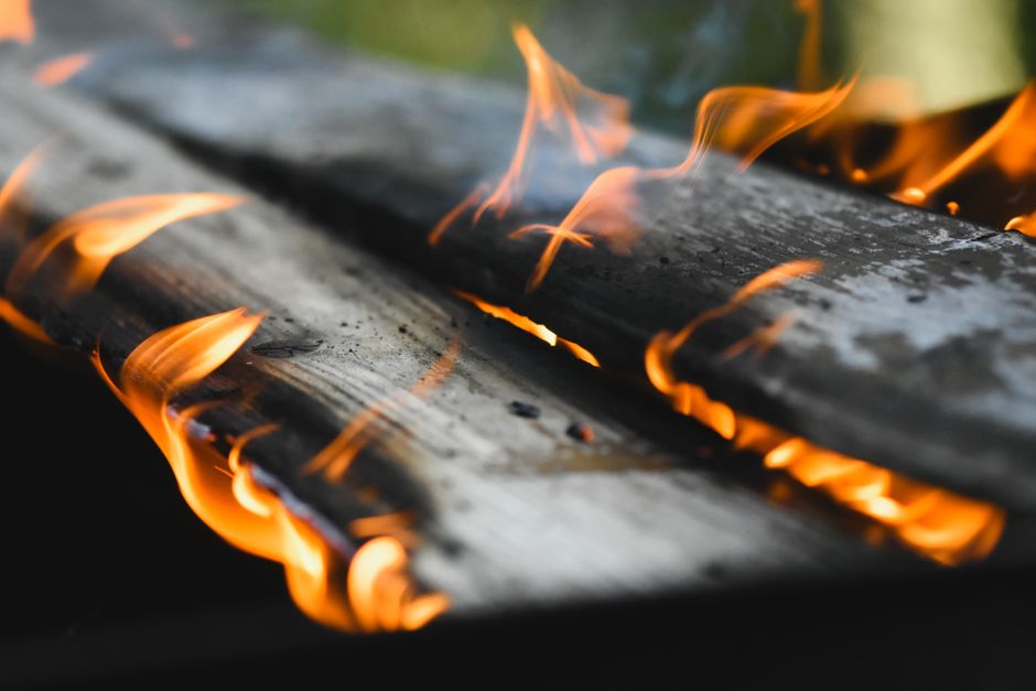 Vivid flames engulf wooden planks in an outdoor fire setting, showcasing warmth and energy.